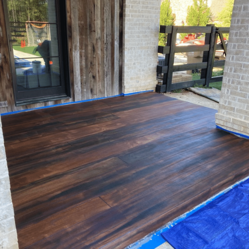 Our Work - Photo of a rustic wood concrete patio featuring a textured surface with a wood grain pattern that closely resembles natural wood. This durable and low-maintenance outdoor living space provides a practical and stylish option for homeowners to enjoy.