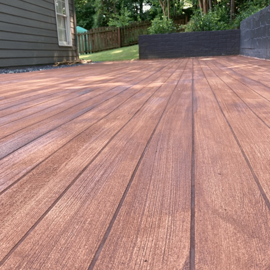 Photo of a rustic wood concrete patio featuring a textured surface with a wood grain pattern that closely resembles natural wood. This durable and aesthetically pleasing outdoor living space offers the perfect balance of style and functionality for homeowners to enjoy.