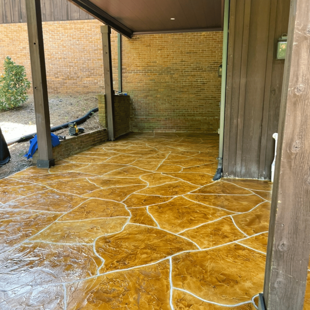 Our Work - Photo of a stamped concrete patio featuring a decorative pattern that closely resembles natural stone. This outdoor living space offers a durable, low-maintenance, and aesthetically pleasing option for homeowners to enjoy.